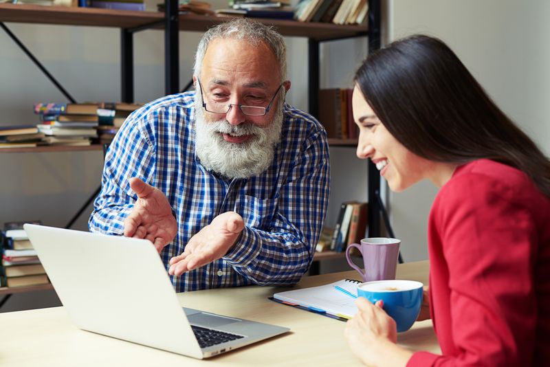 excited colleagues discussing something and looking at laptop in office